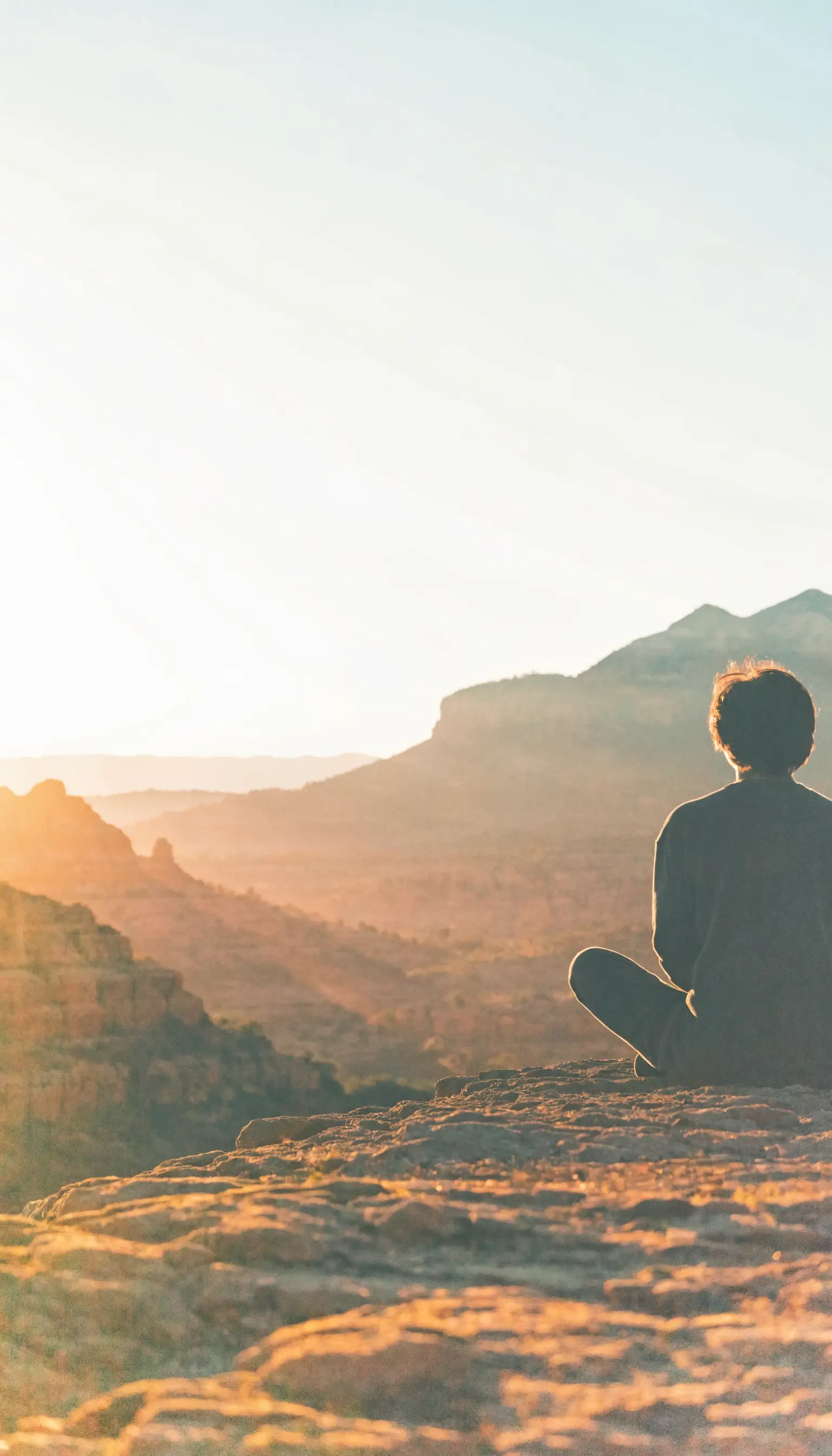 A person sitting quietly on a ridge above Sedona at first light
